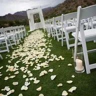 A row of white chairs sitting on top of a lush green field.
