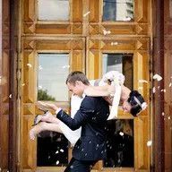 A bride and groom are posing for a picture in front of a wooden door.