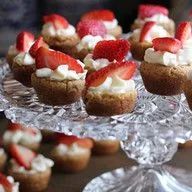 A glass plate topped with cupcakes with strawberries and whipped cream.
