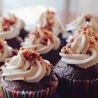 A close up of a bunch of chocolate cupcakes with frosting on a table.