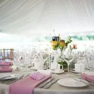 A table set for a wedding reception with pink napkins and plates.