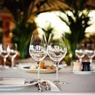 Two wine glasses are sitting on a table with plates and silverware.