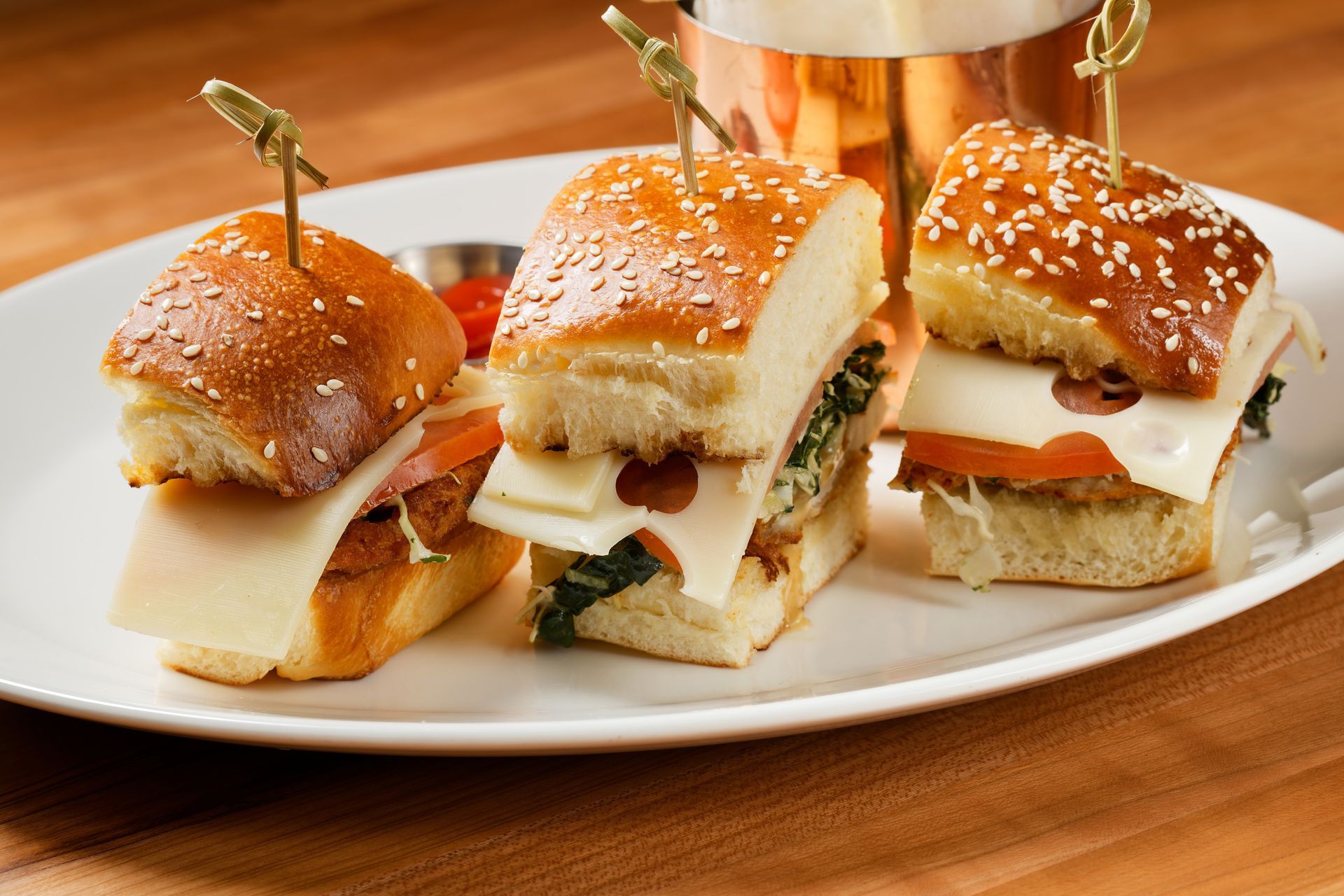 A white plate topped with three sandwiches on toothpicks.