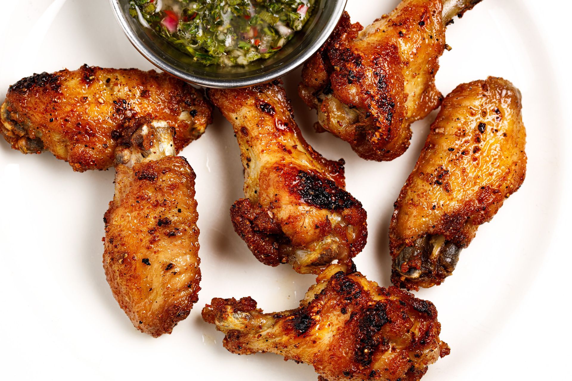 A white plate topped with chicken wings and a bowl of dipping sauce