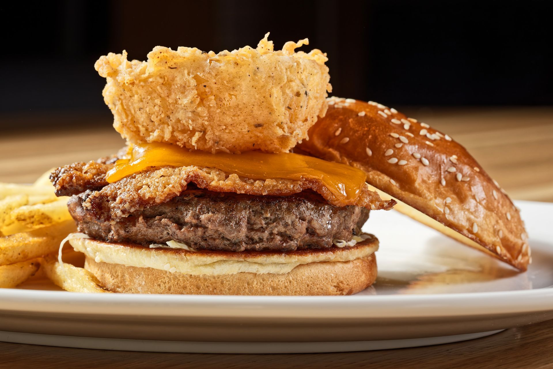 A close up of a hamburger on a plate with fries.