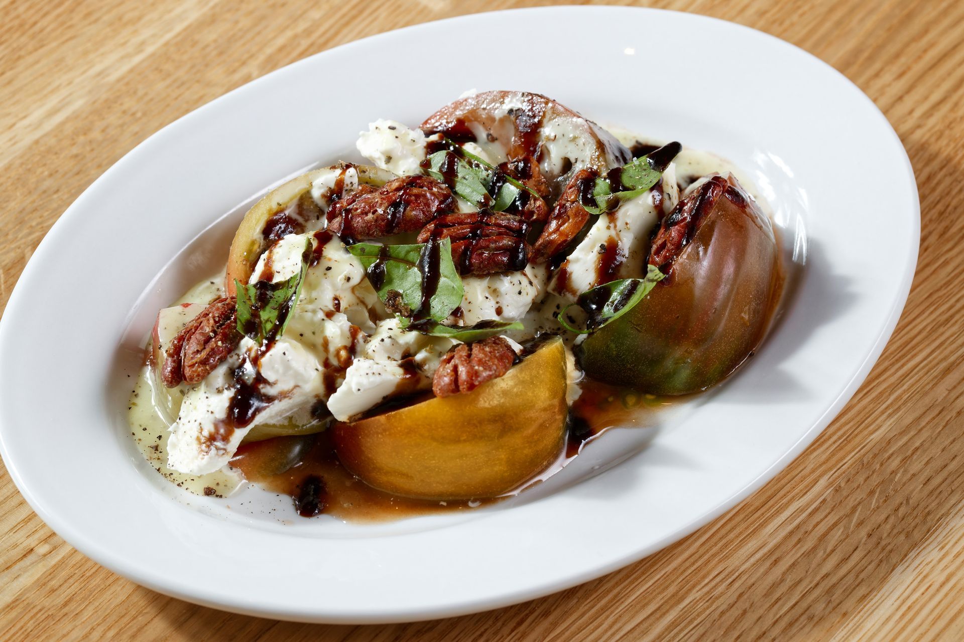 A white plate topped with a salad on a wooden table.