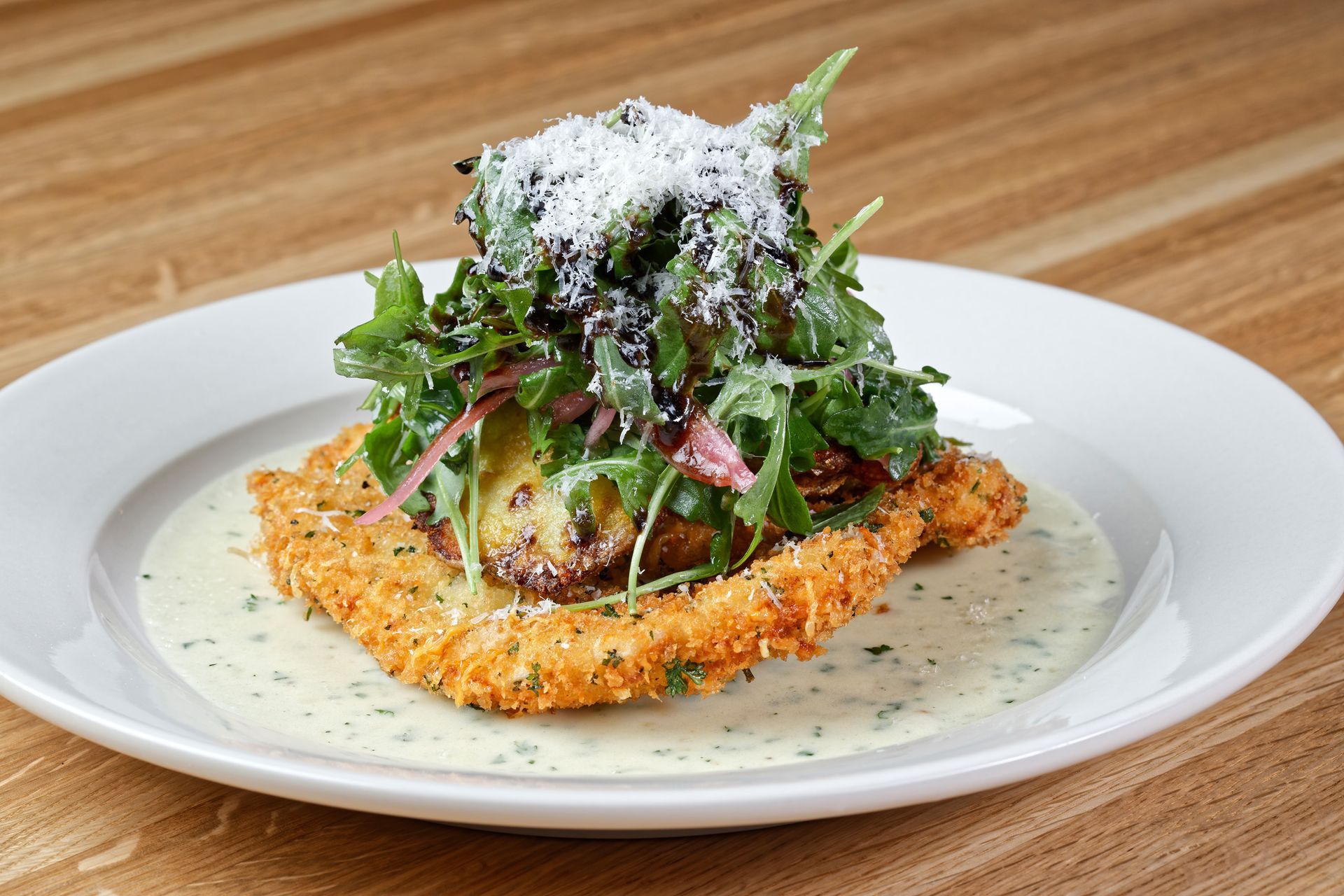 A plate of food with a salad on top of it on a wooden table.