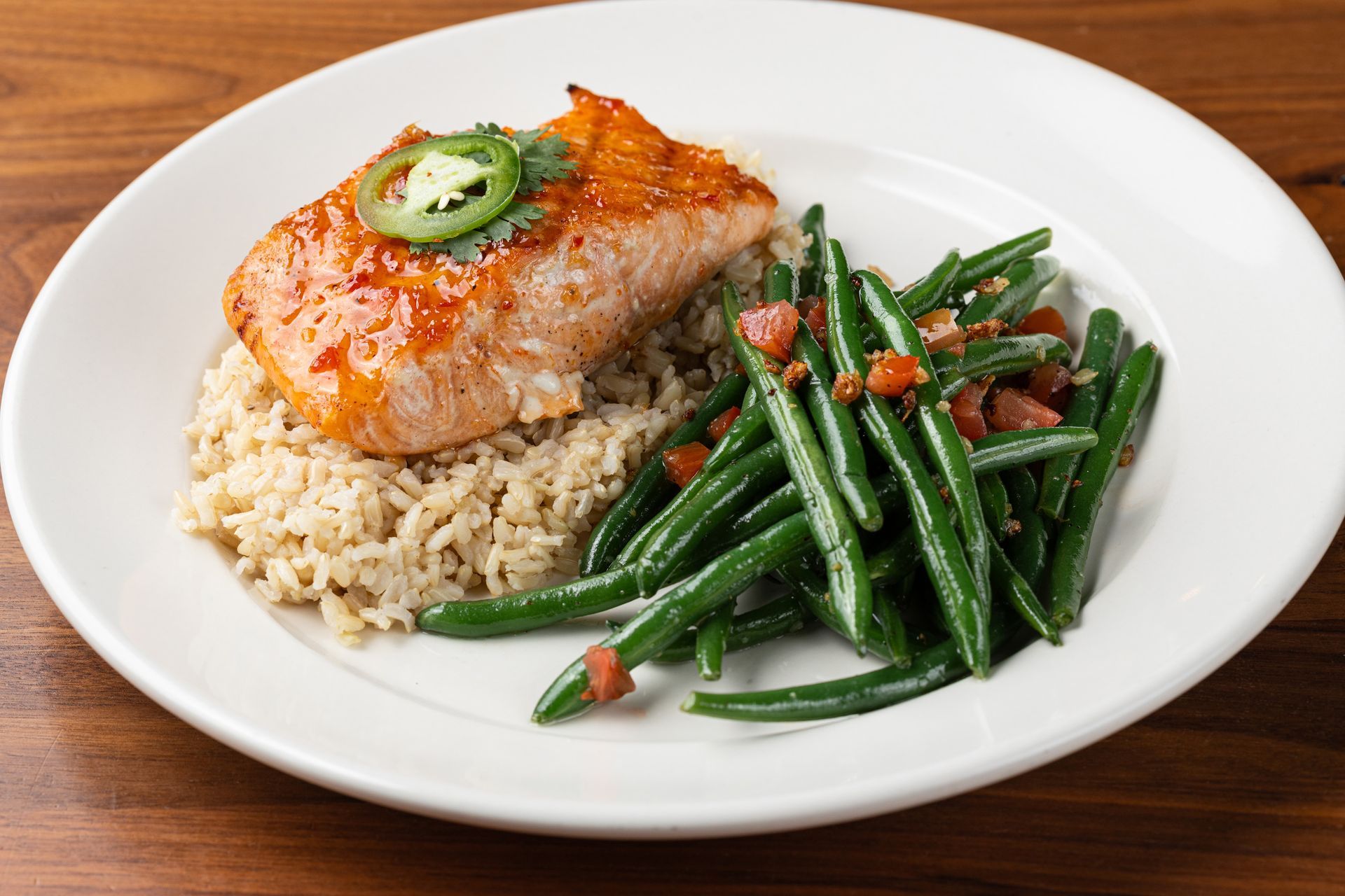 A plate of food with green beans and rice on a wooden table.