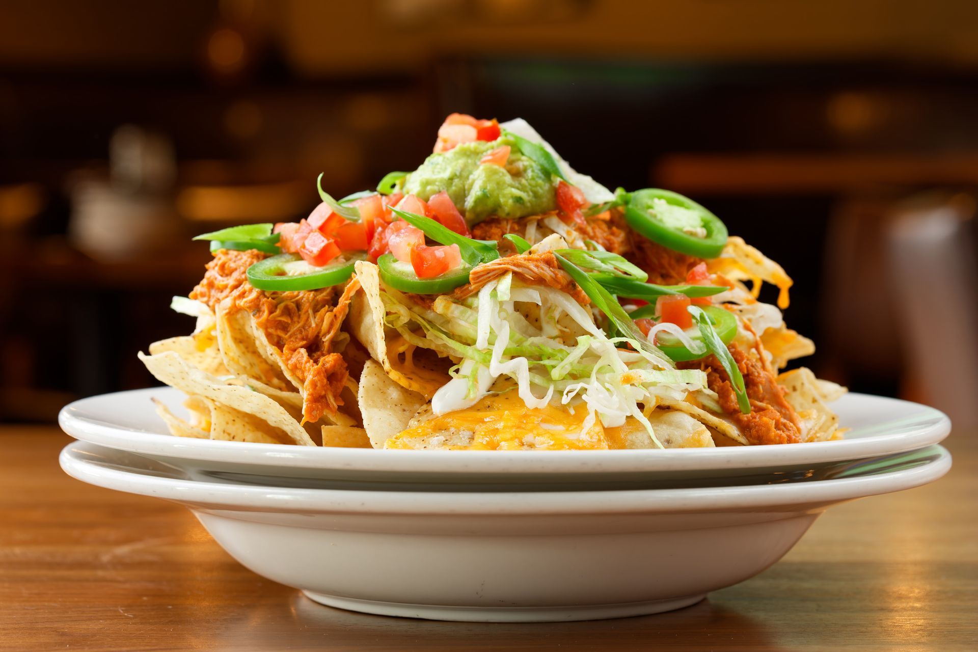 A close up of a plate of nachos on a table.