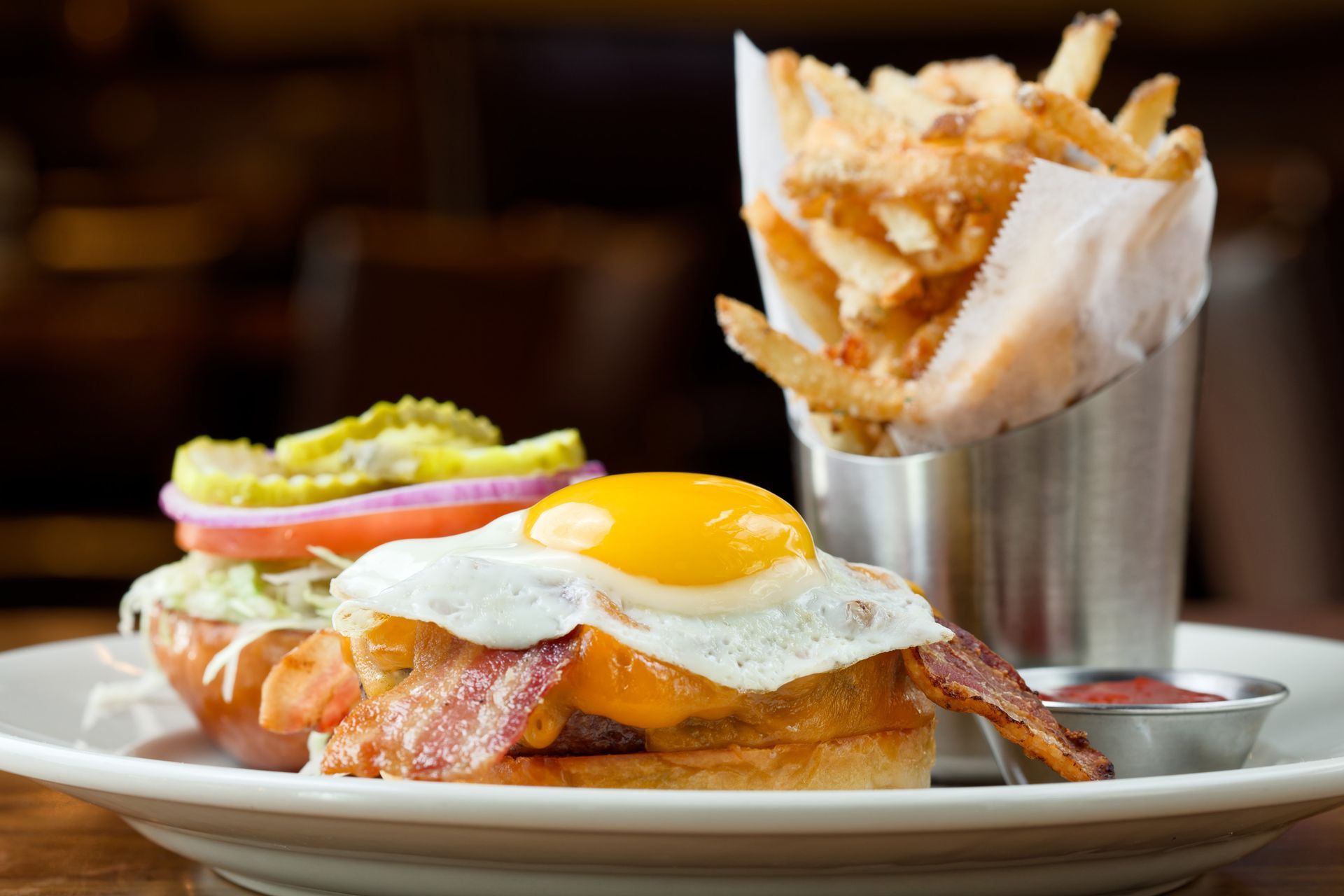 A plate of food with eggs , bacon and french fries on a table.
