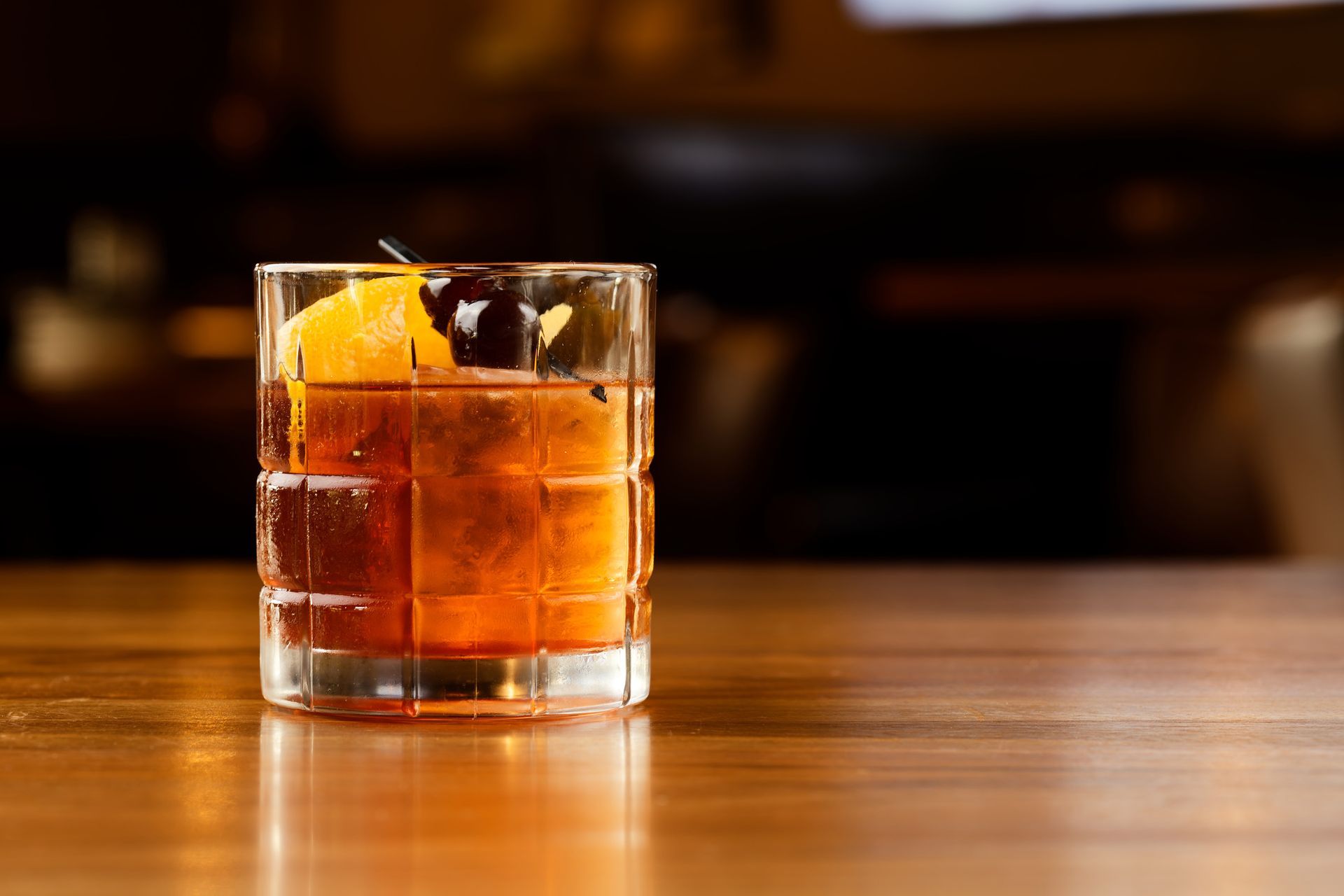 A close up of a glass of whiskey on a wooden table.