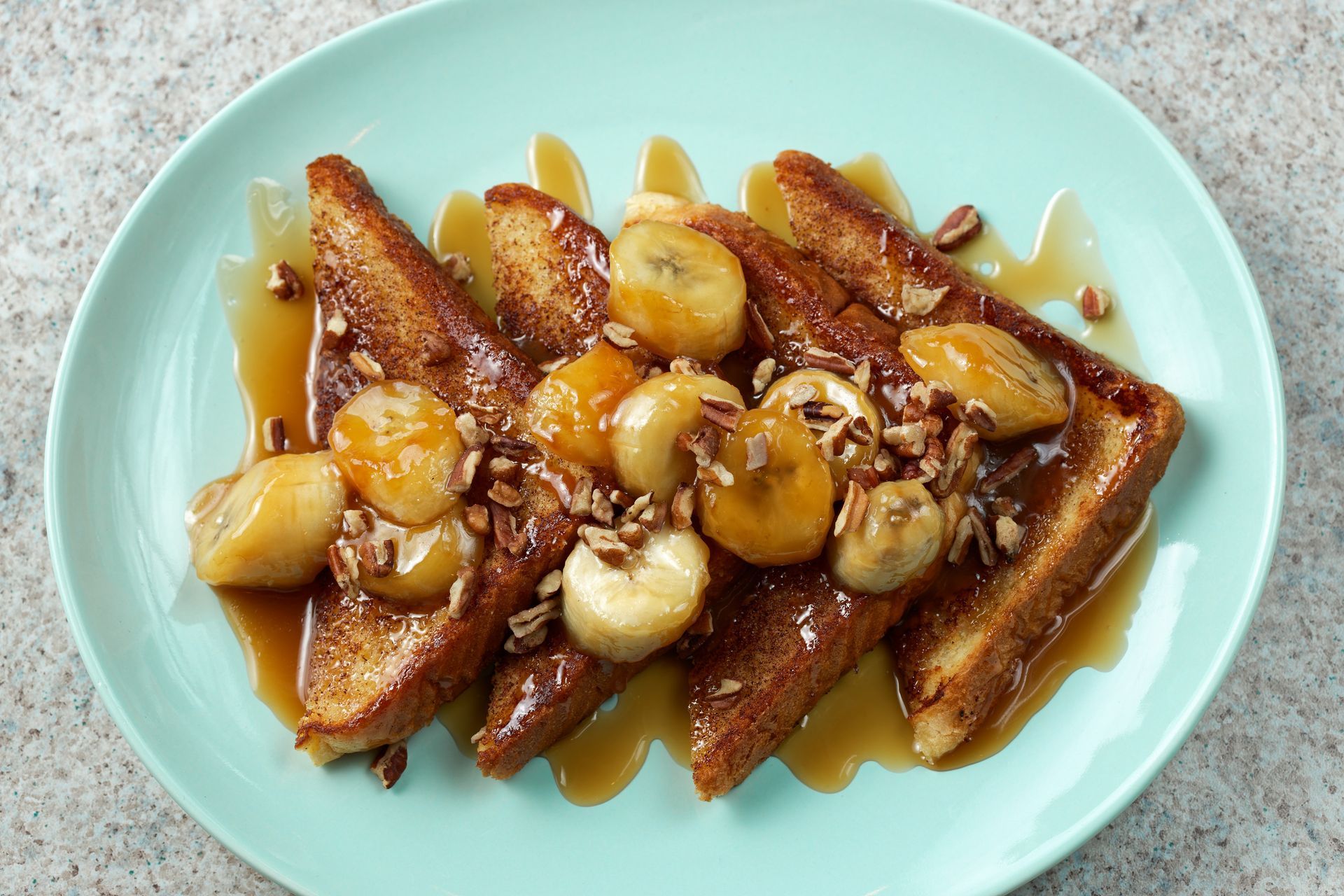 French toast with bananas and pecans on a blue plate