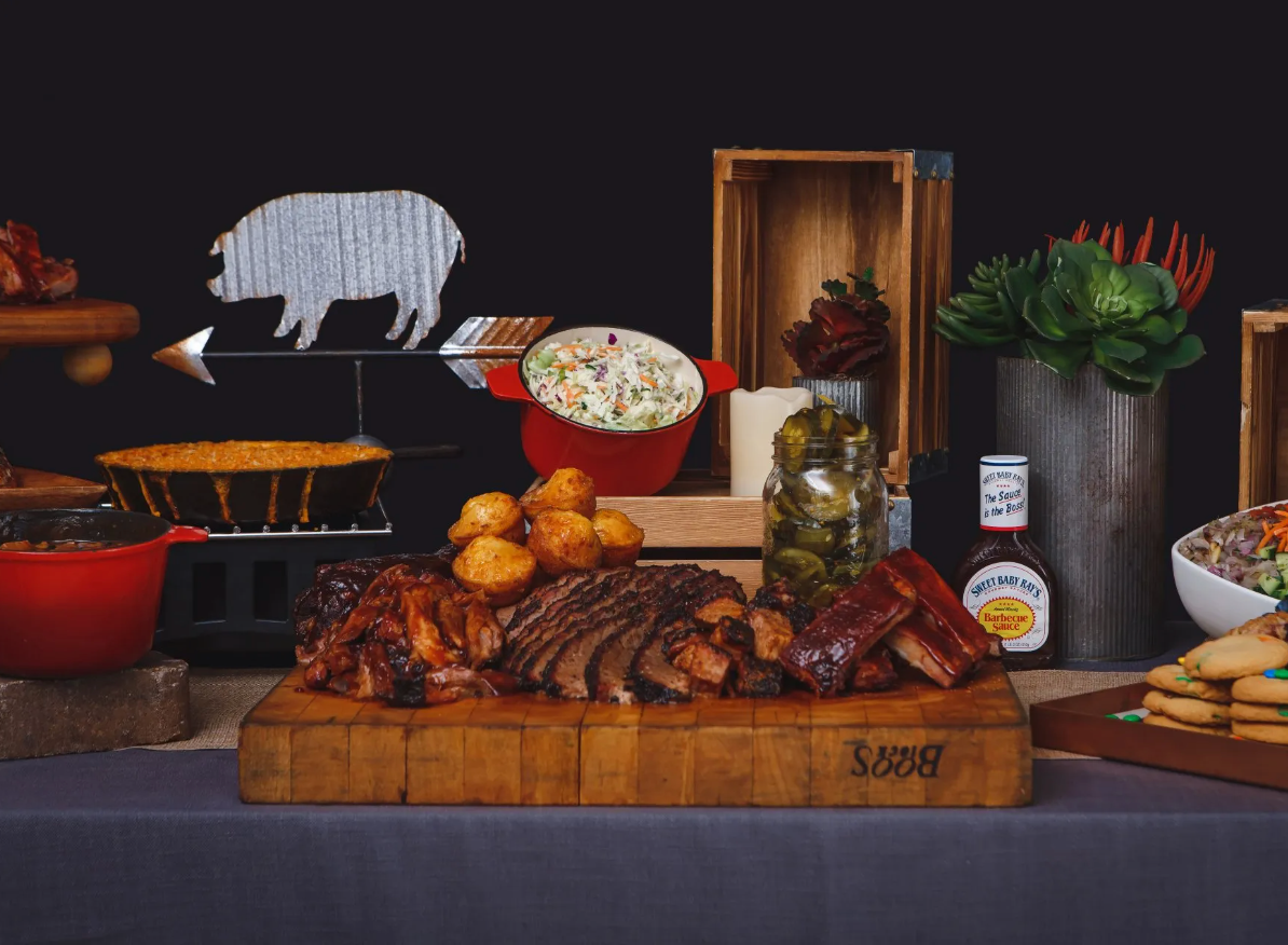 A wooden cutting board filled with meat and vegetables on a table.