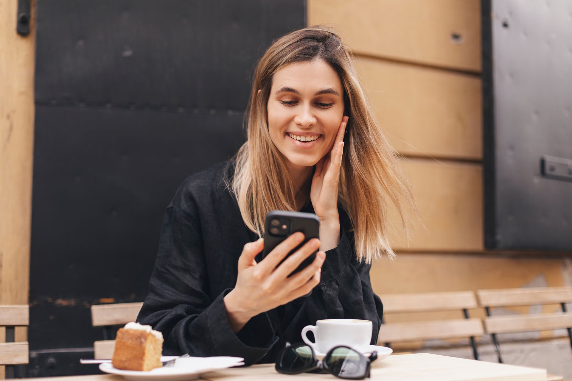 A woman is sitting at a table looking at her cell phone.