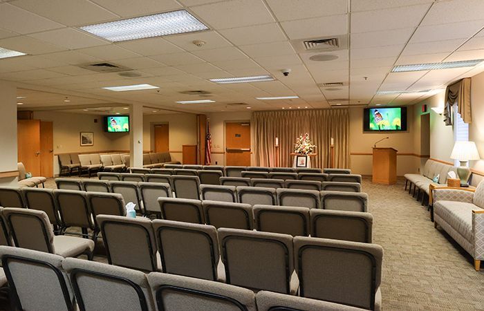 A large room with rows of green chairs and a podium