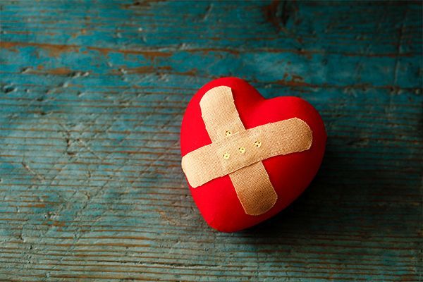 a red heart with a bandage on it is sitting on a wooden table .