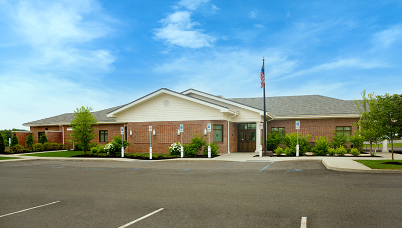 A large brick building with columns and a lush green lawn in front of it.
