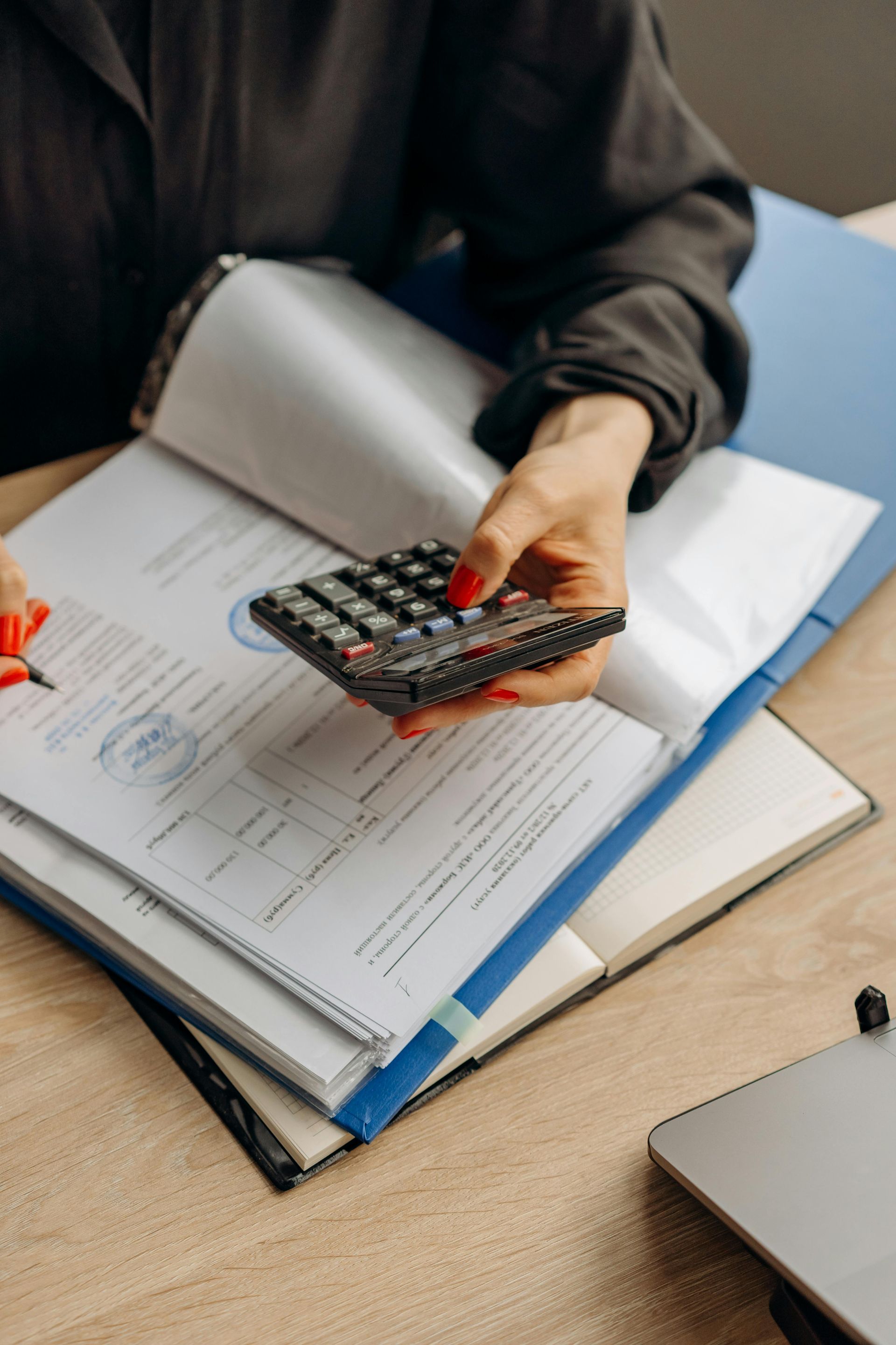 A woman is holding a calculator in her hand while sitting at a desk.