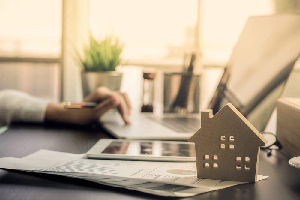 A Model House Is Next To A Person Using A Laptop  — GMS Legal & Conveyancing In 38 Canton Beach Rd Toukley, NSW