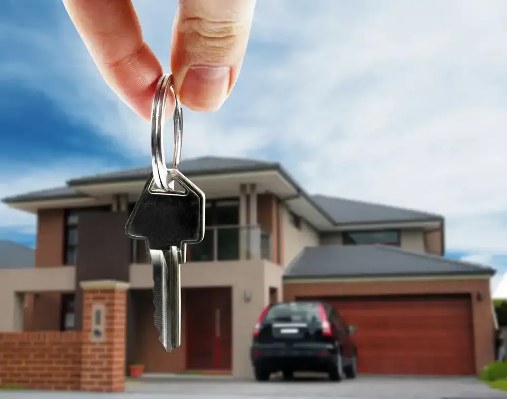 Hand holding keys in front of a modern house and car, likely symbolizing homeownership. GMS Legal & Conveyancing In 38 Canton Beach Rd, Toukley