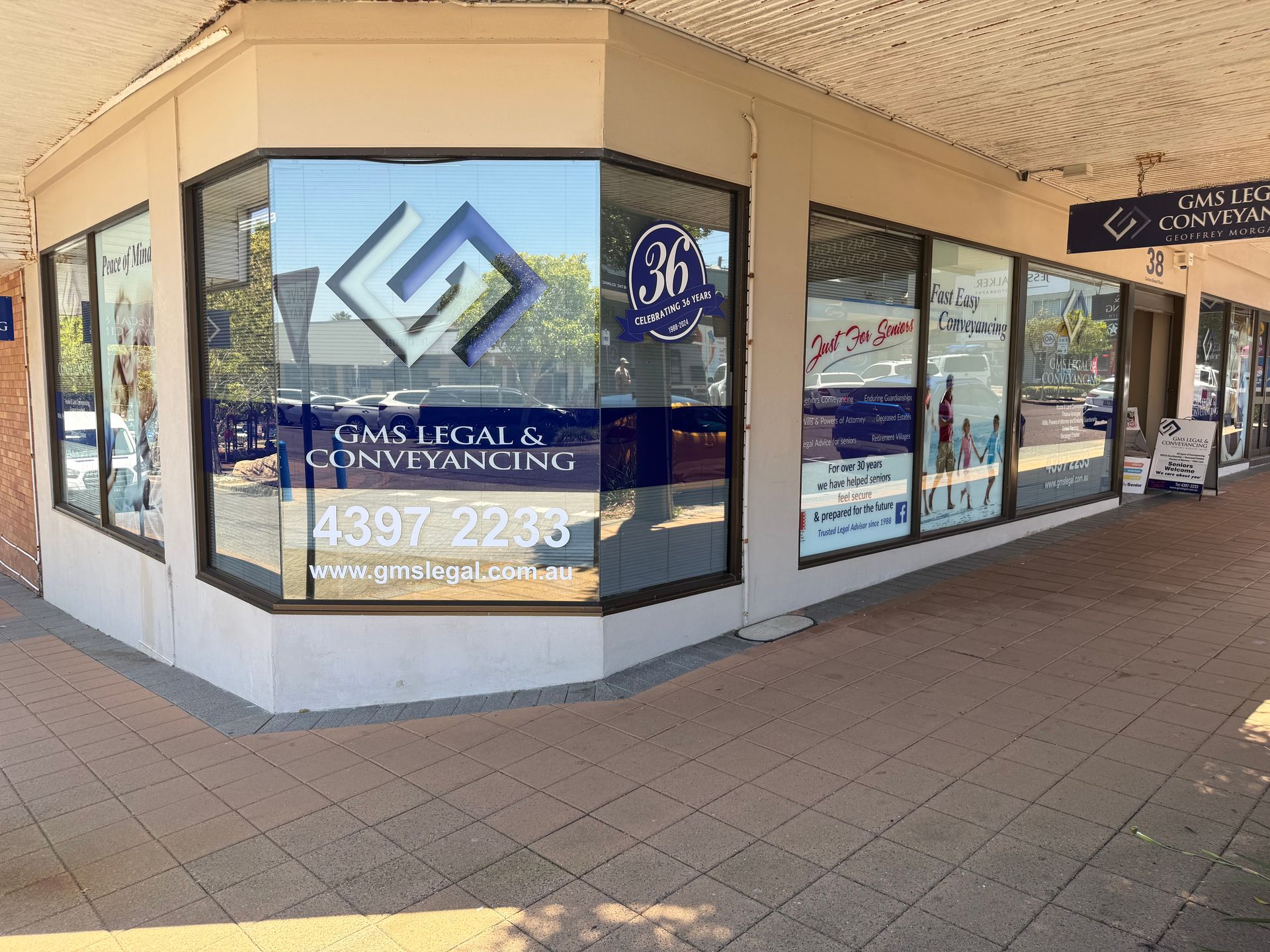 A Man And A Woman Are Sitting At A Table With A Laptop — GMS Legal & Conveyancing In 38 Canton Beach Rd, Toukley