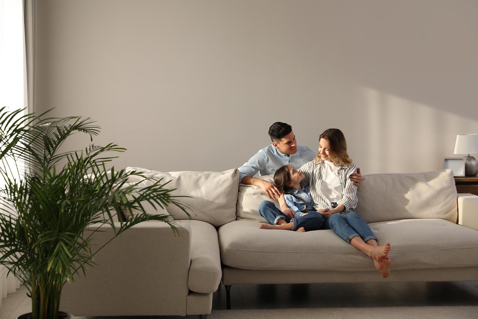 Family Sitting On The Sofa On Their New Home