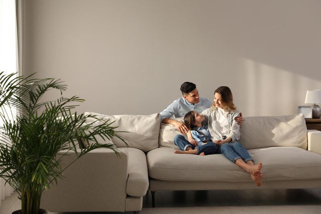 Family of Three on a Cream Sofa in a Bright Room — GMS Legal & Conveyancing In 38 Canton Beach Rd, Toukley