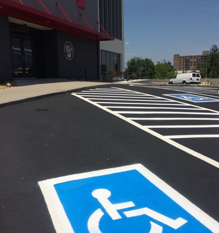 Accessible parking spaces and striped curb area outside a building on a sunny day