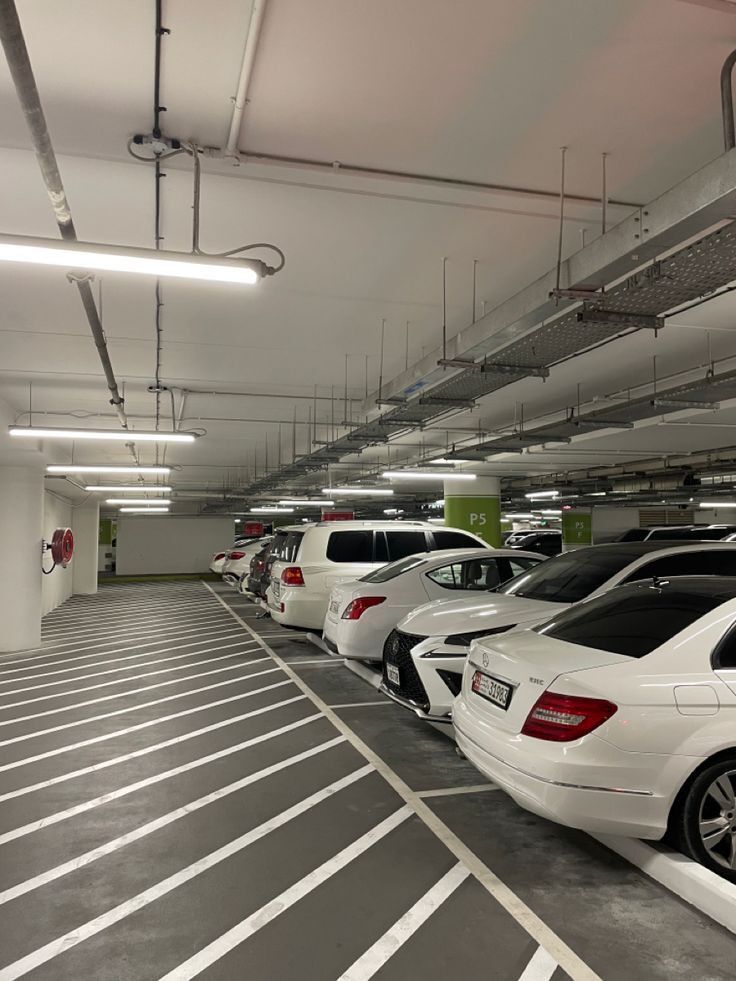 Underground parking garage with rows of white cars and bright ceiling lights