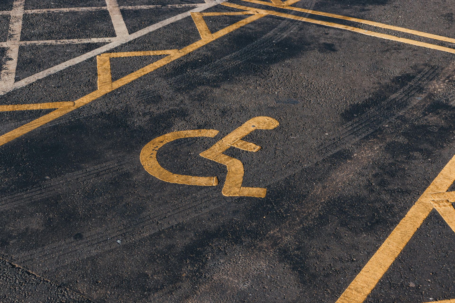 Accessible parking space marked with a yellow wheelchair symbol on dark asphalt
