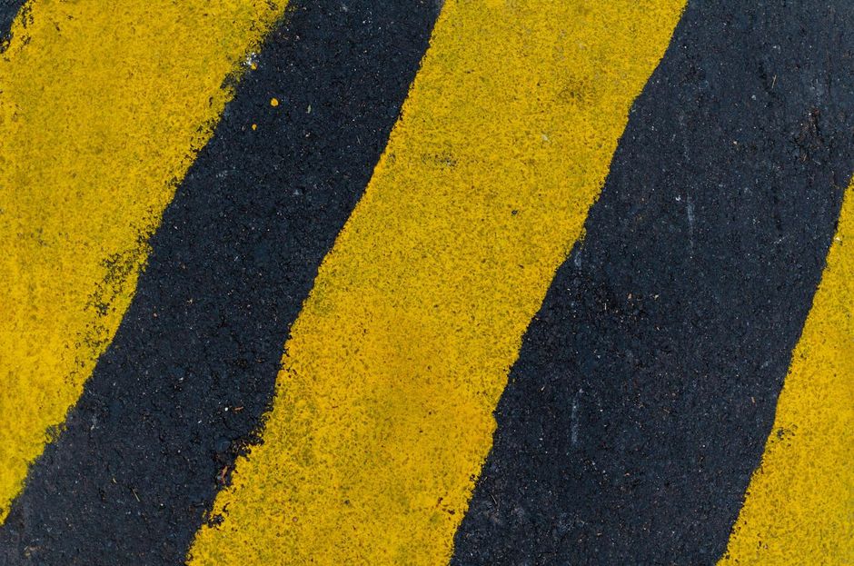 Yellow and black diagonal hazard stripes on a rough painted surface