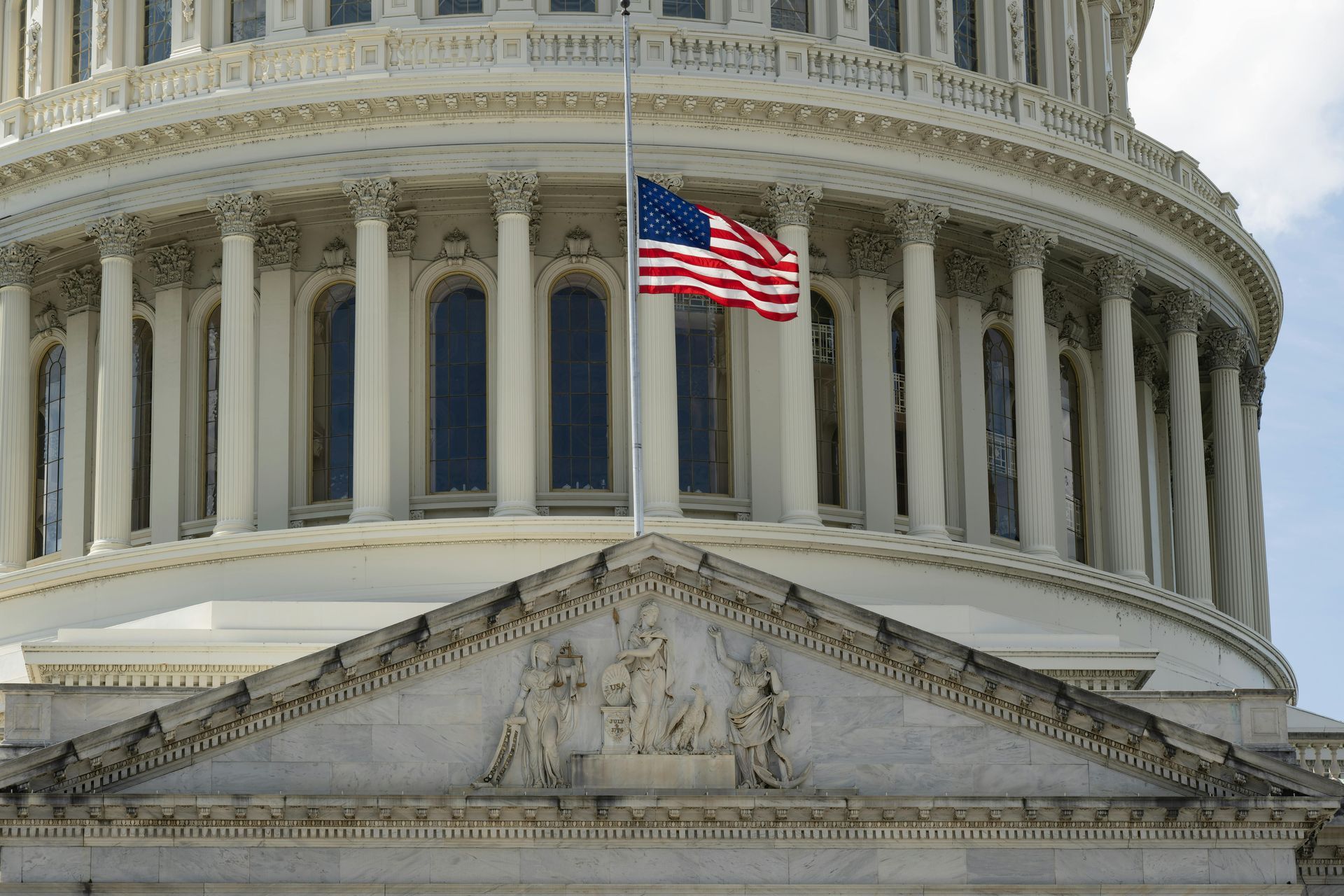 U.S. Capitol dome with an American flag above the pediment.