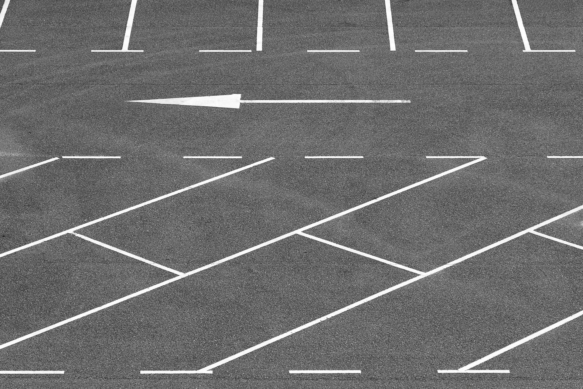 Empty parking lot with white painted lines and arrows on gray pavement