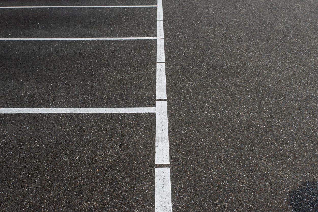 Empty parking lot with white painted lines on dark asphalt