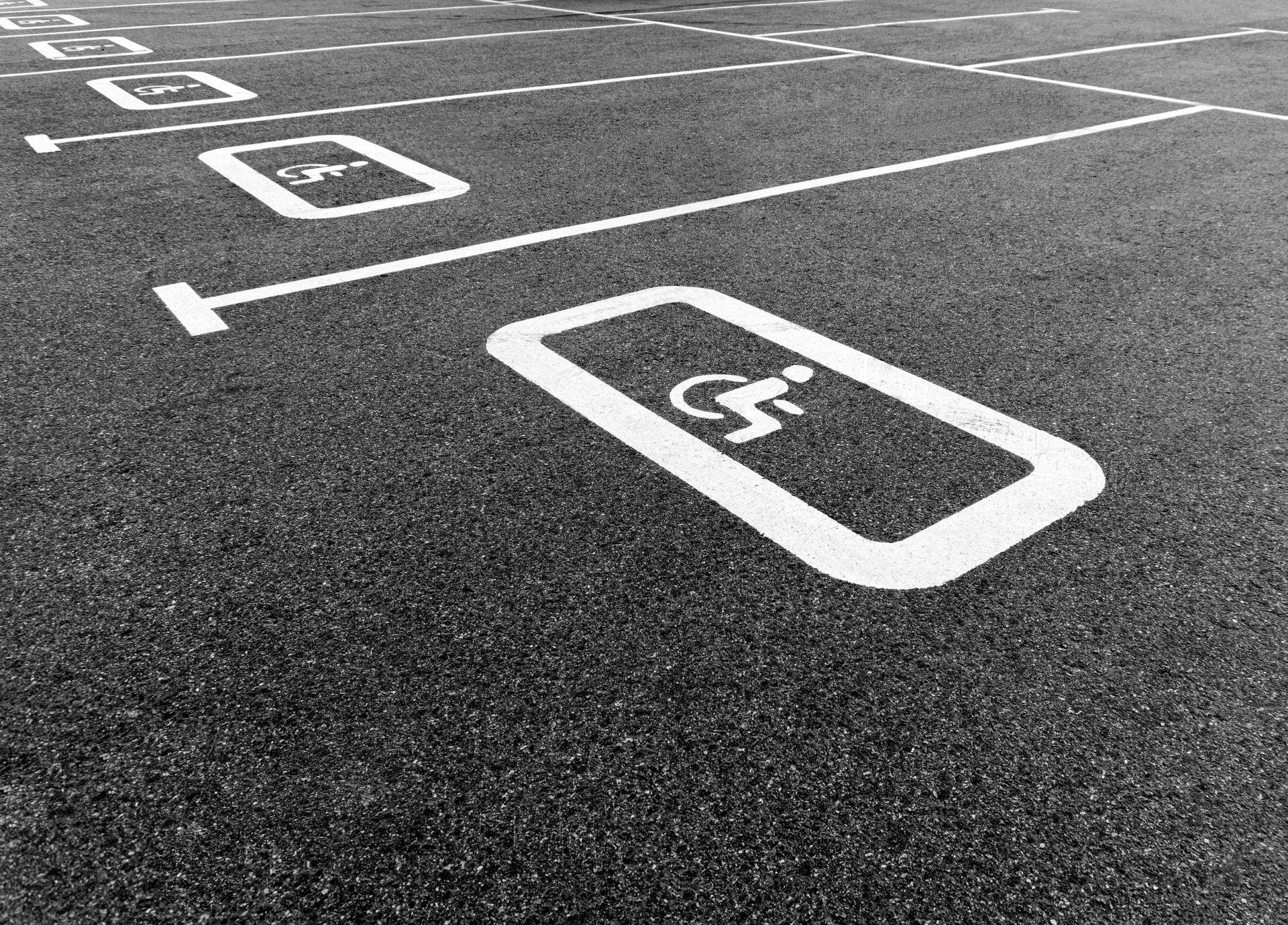 Empty accessible parking spaces marked on asphalt in a black-and-white lot