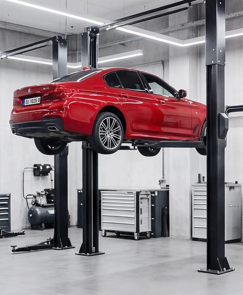 Red sports car lifted on a hydraulic vehicle hoist in a garage workshop