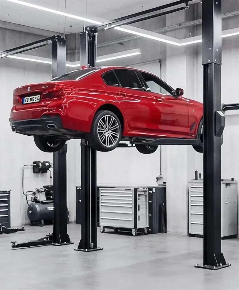 Red sports car lifted on a hydraulic vehicle hoist in a garage workshop