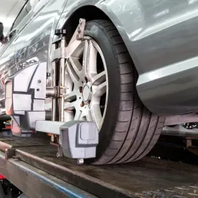 Silver car on a wheel alignment machine in an auto repair shop