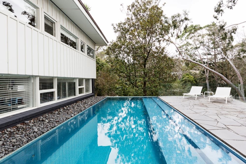 There is a Large Swimming Pool in Front of a House — Aqualine Pools in Coral Cove, QLD
