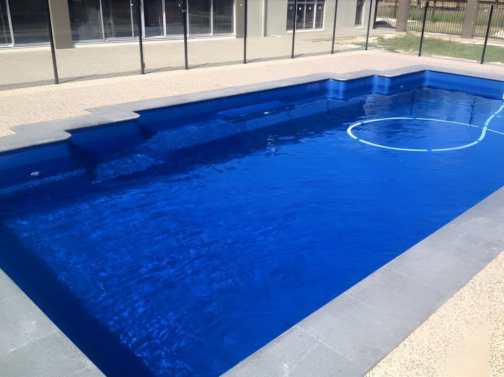 A Large Blue Swimming Pool With a Fence Around It — Aqualine Pools in Branyan, QLD