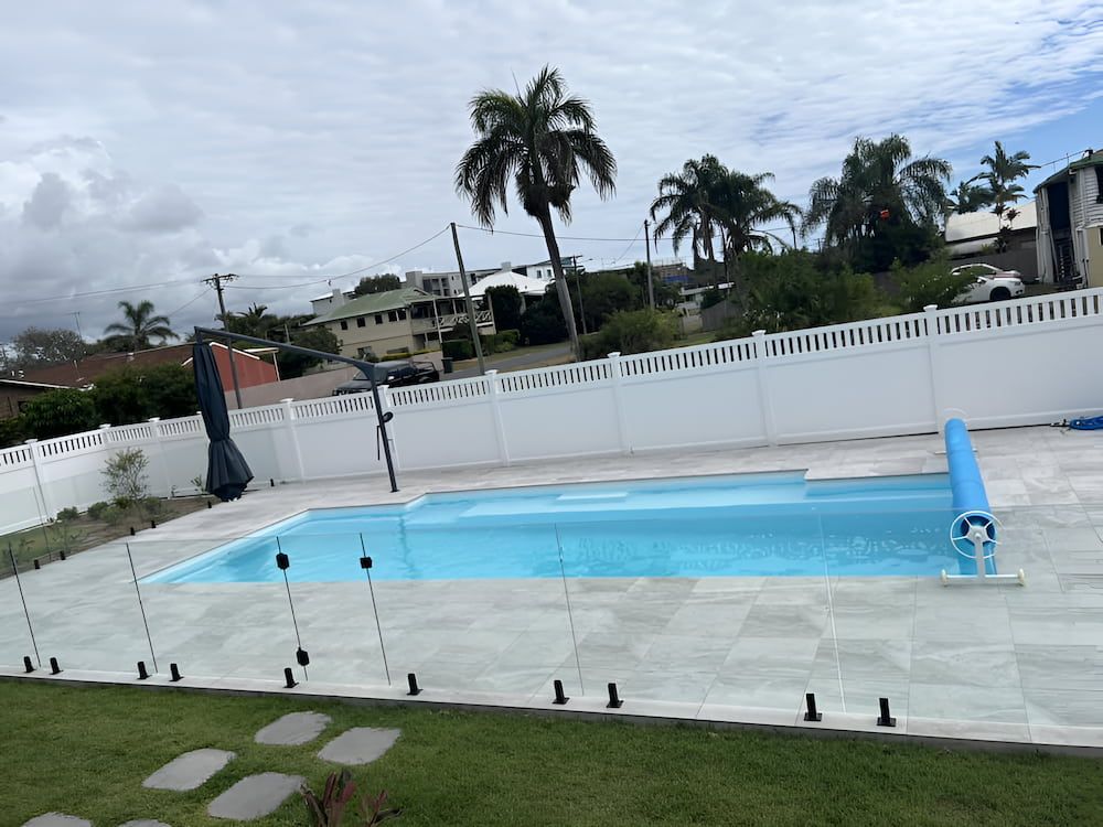 A Large Swimming Pool Surrounded by a Fence and Chairs — Aqualine Pools in Branyan, QLD