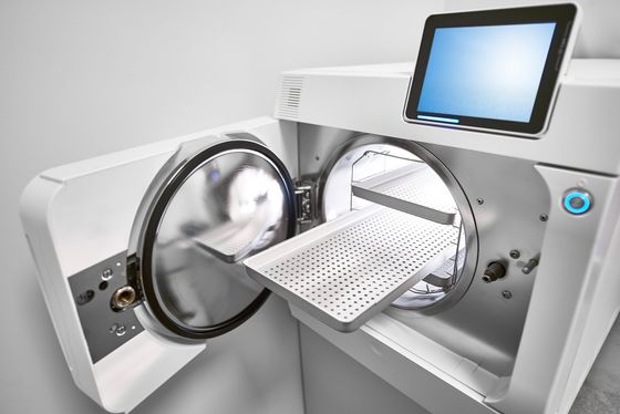 A white washing machine with the door open and a tablet on top of it.