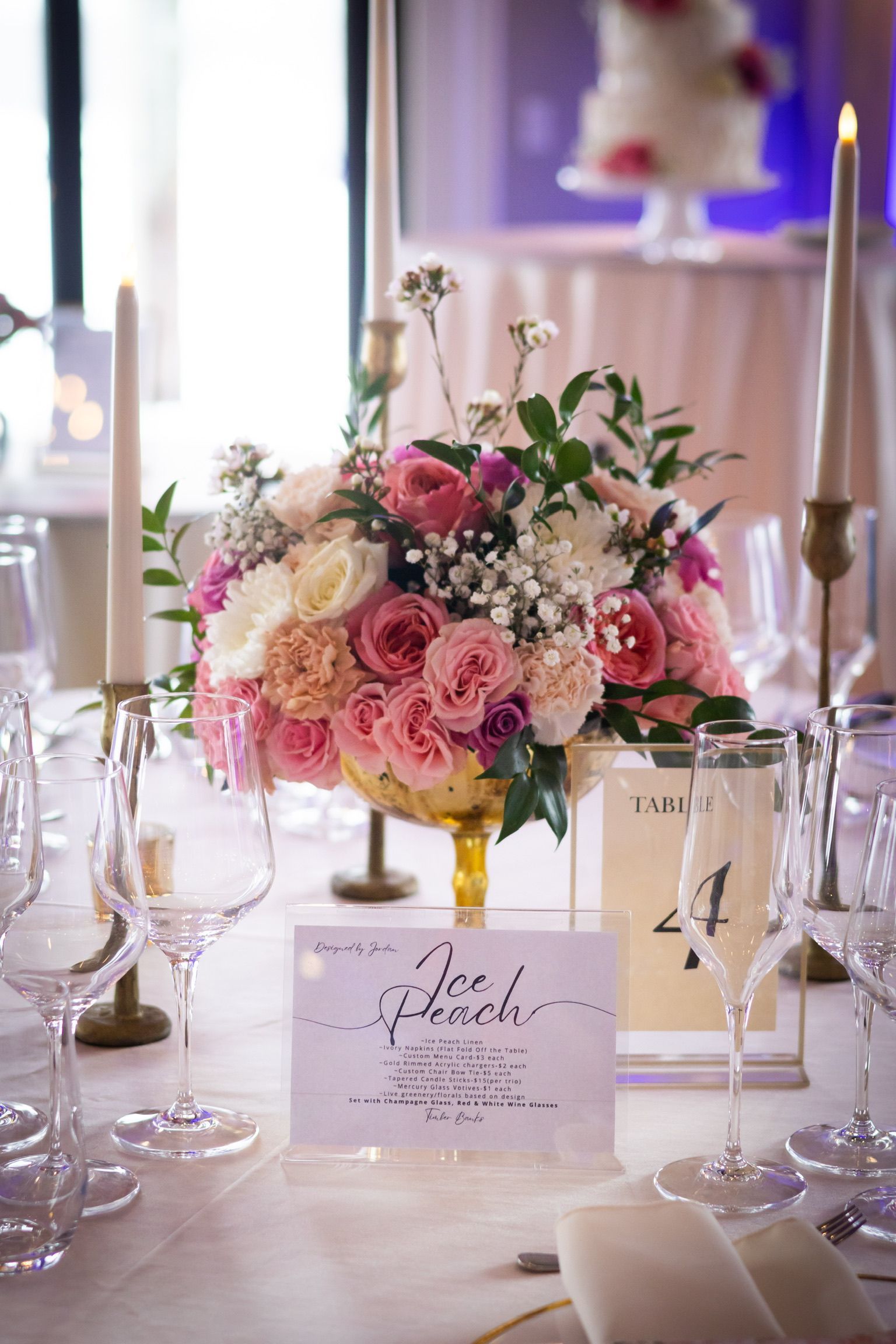 Wedding reception table setting with floral centerpiece, candles, and place cards.