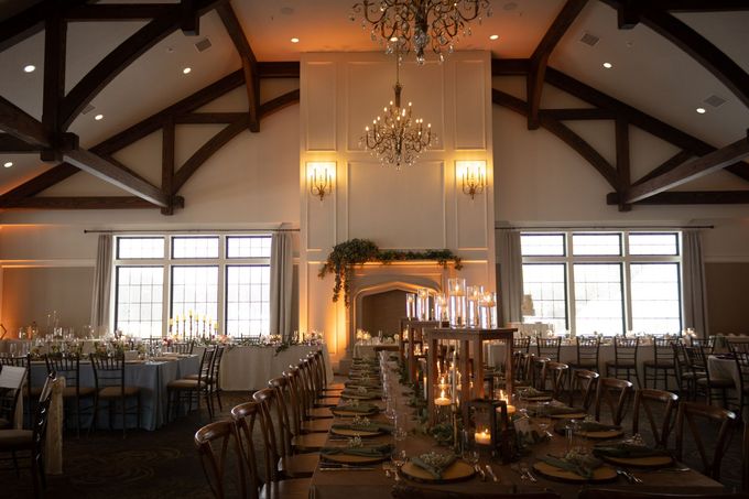 Banquet hall set for event with long tables, candles, and overhead chandelier.