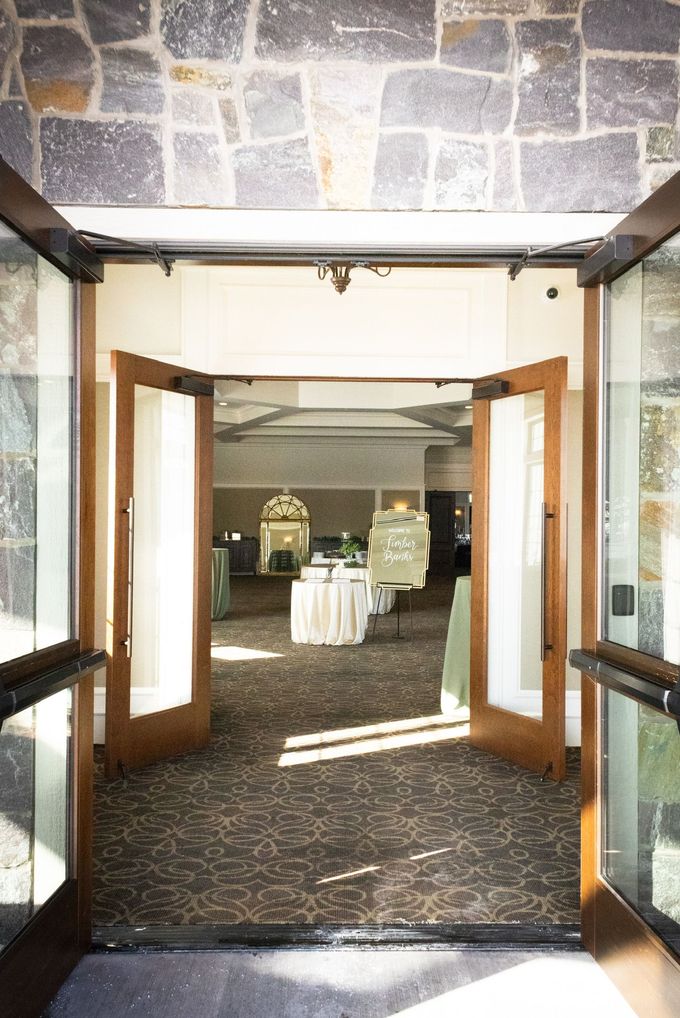 Open double doors leading into a room with tables and decorations. Sunlight streams in, illuminating the interior.