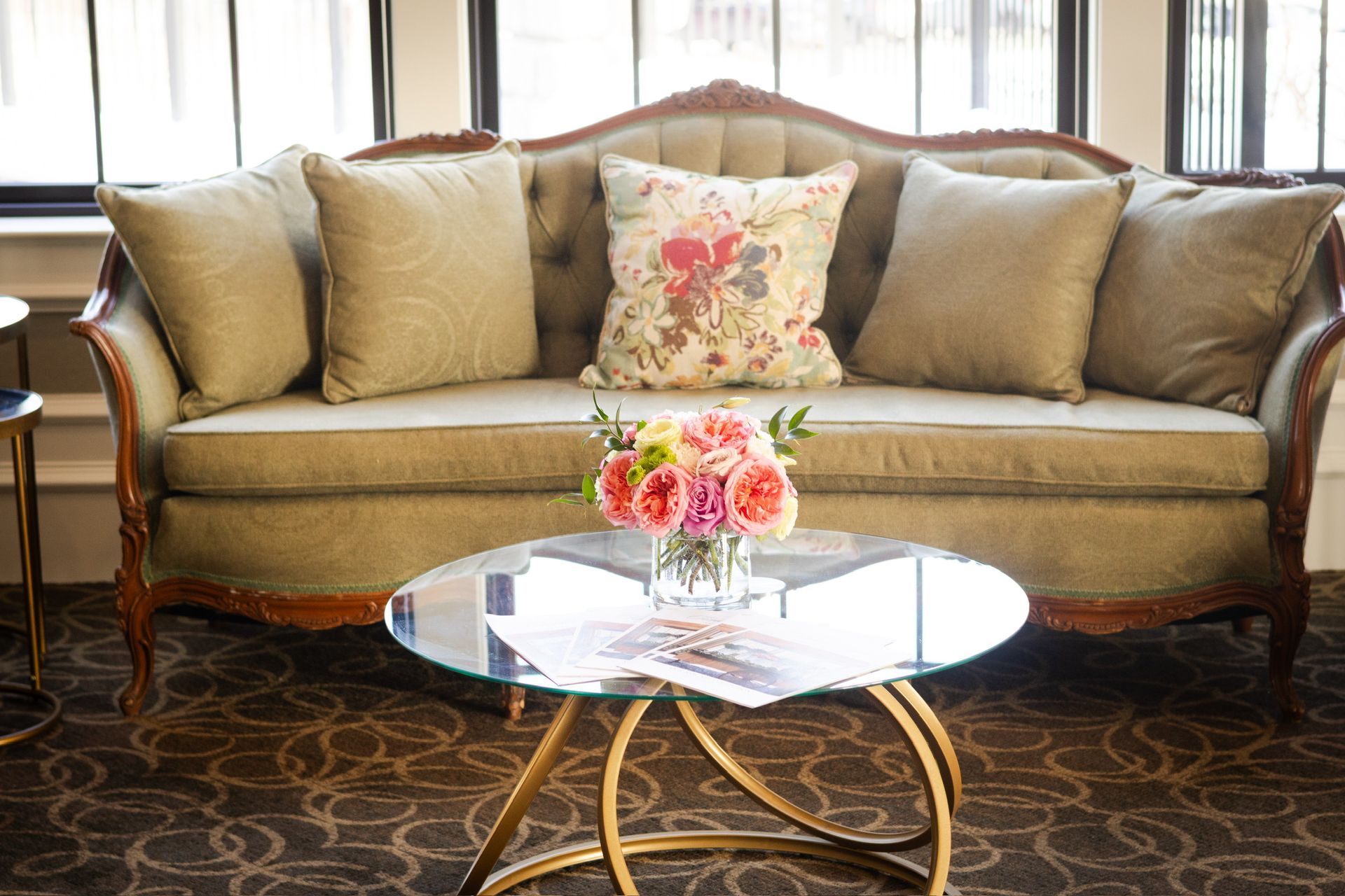 Elegant sofa with cushions, floral centerpiece on a glass table.