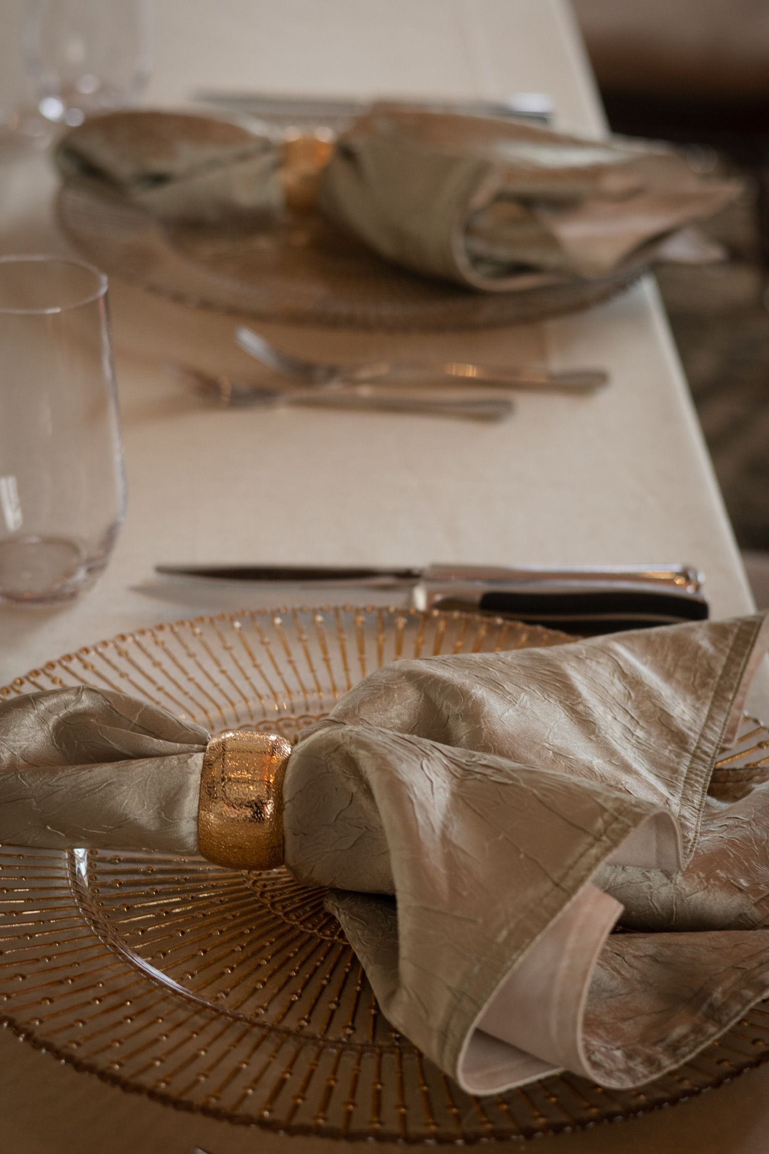 Formal place setting with gold charger, napkin, and silverware.