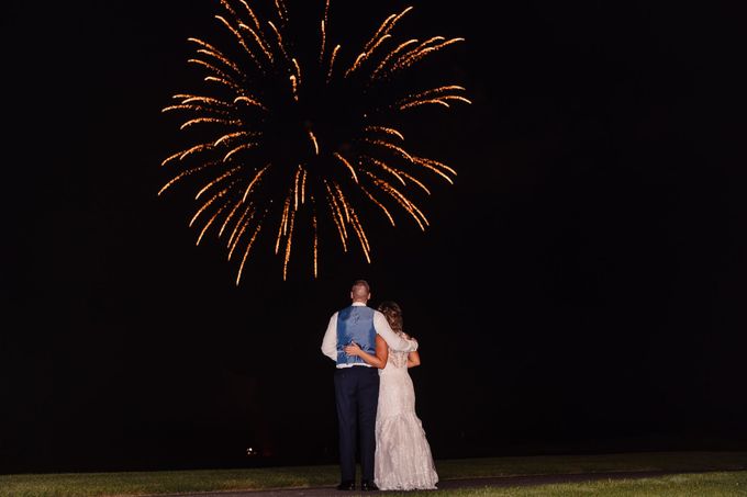 Couple embraces, watching fireworks in night sky.