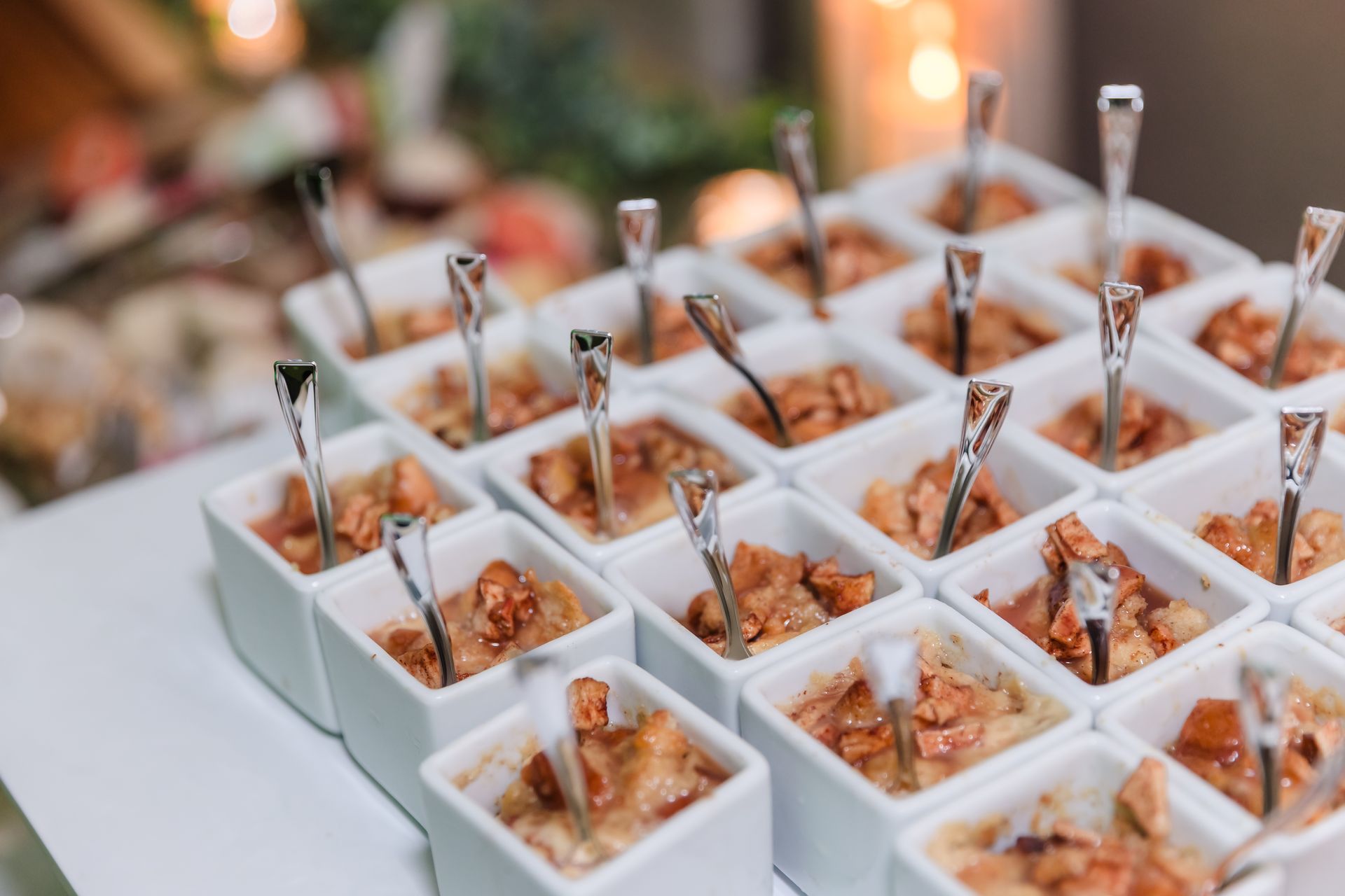 Small white square dishes filled with food, each with a small fork.