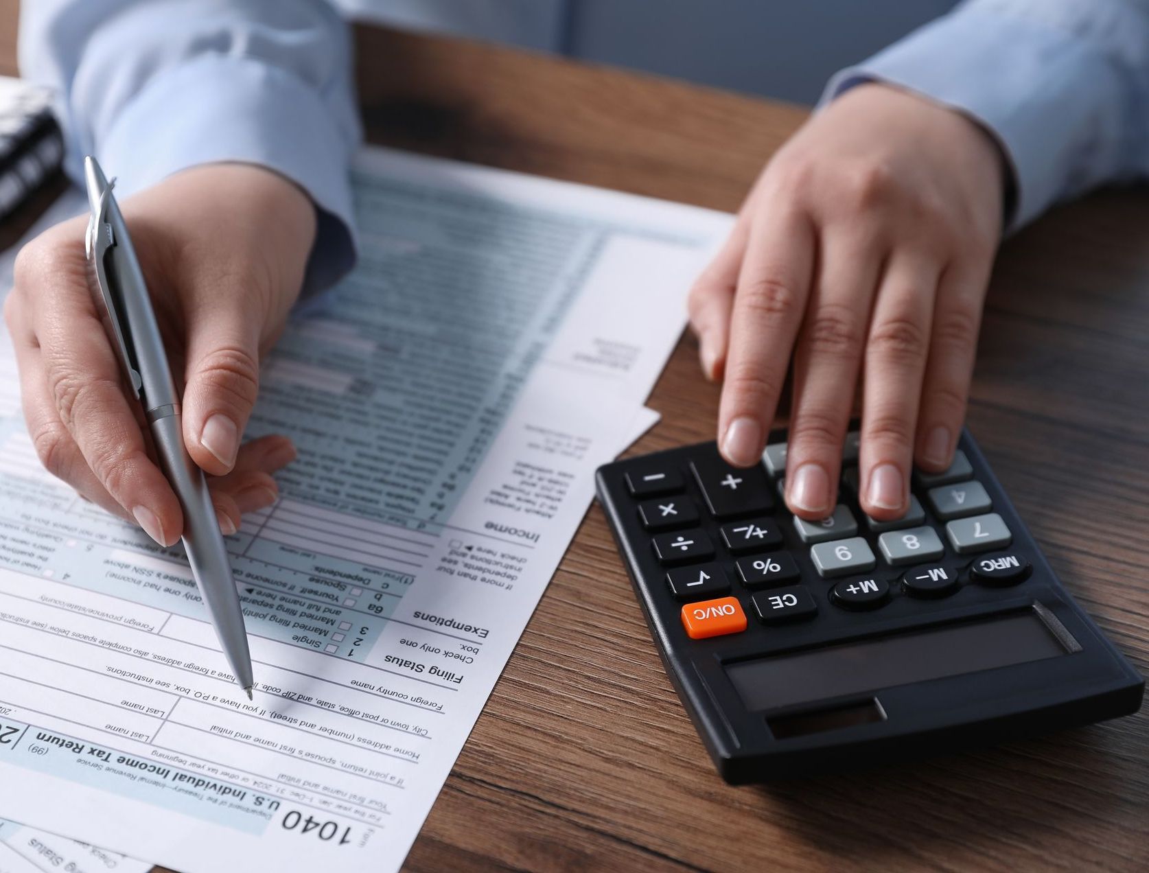 A person is filling out a tax form and using a calculator.